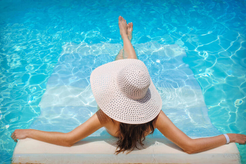 Woman wearing hat relaxing by the pool